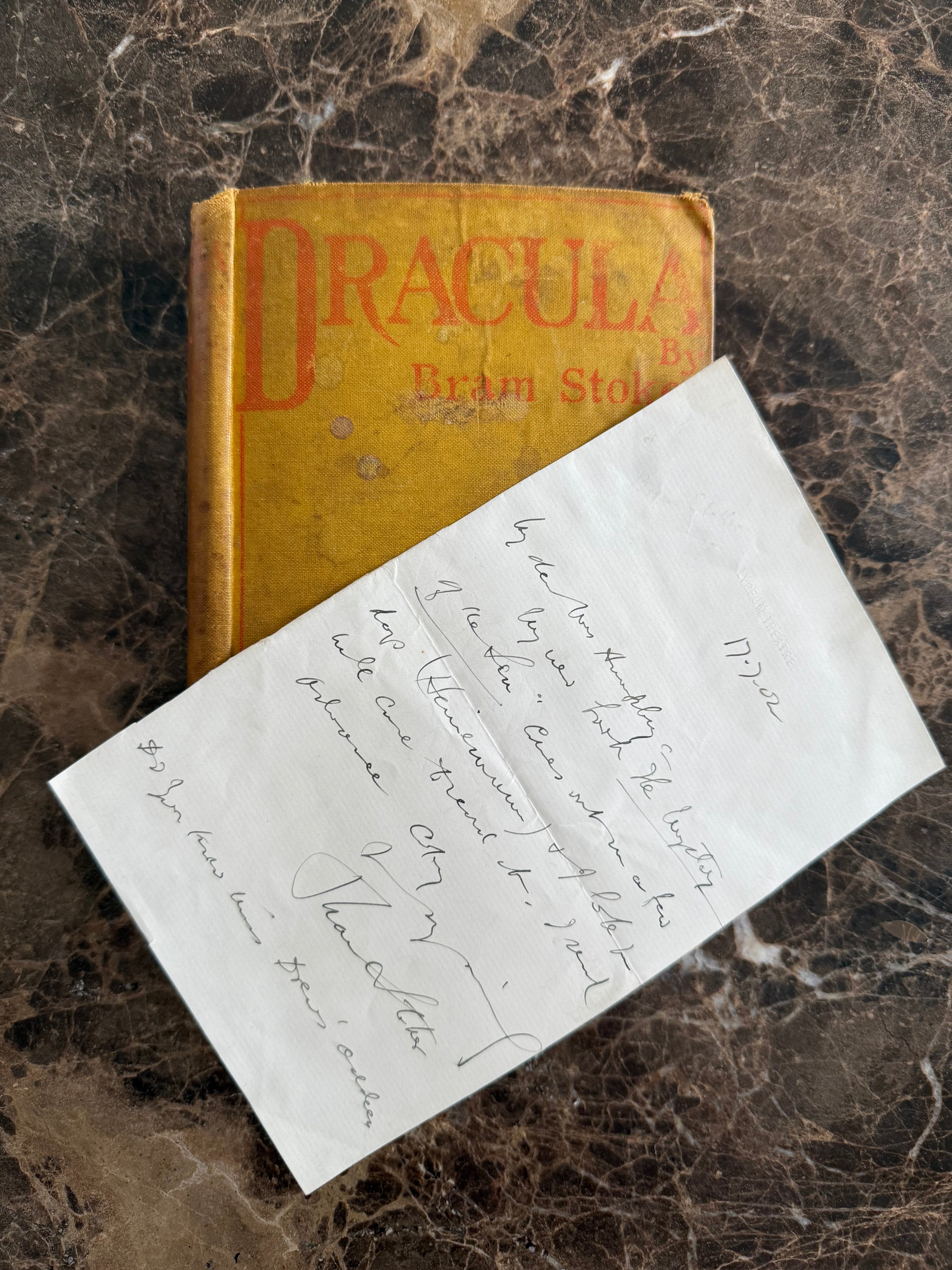 Vintage 'Dracula' book with a handwritten letter on a marble surface
